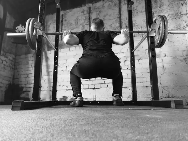 Image of a man squatting inside a power rack.