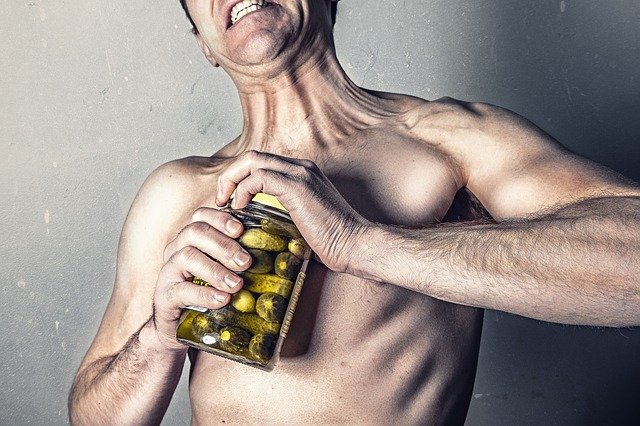 Image of a man trying to open a pickle jar