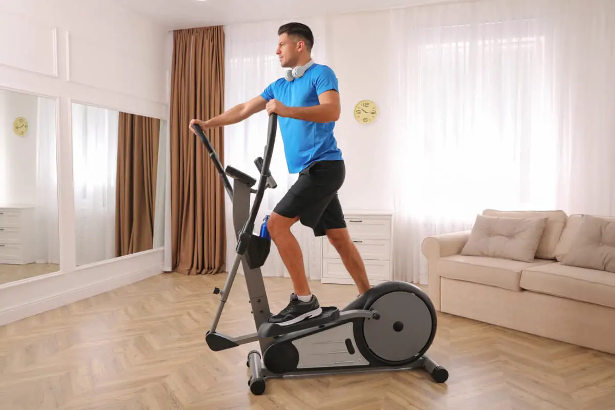 Image of a man on a on an ellipctal trainer in the living rom.