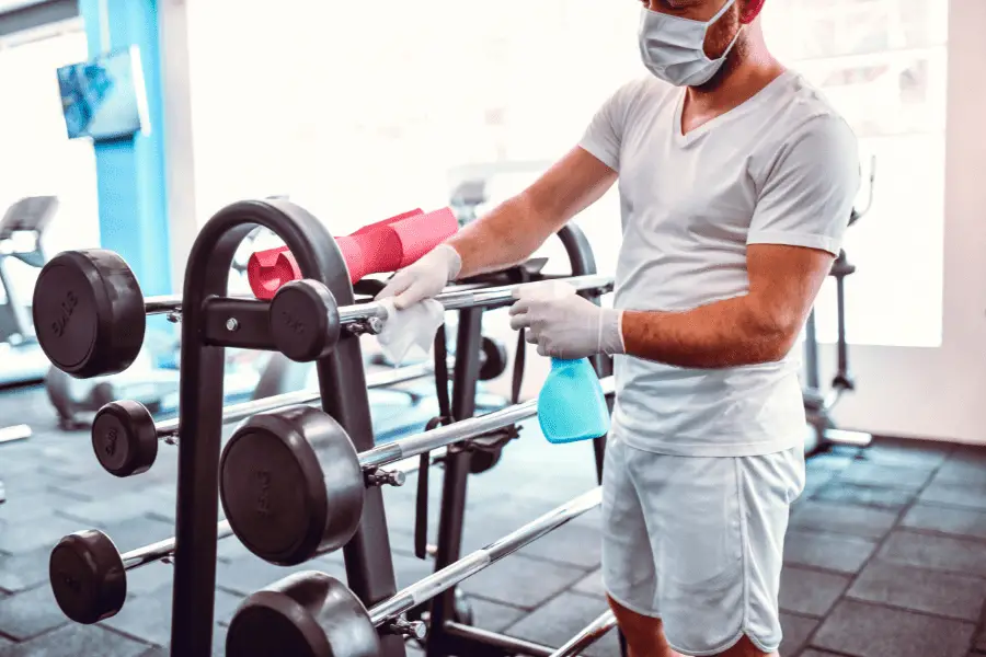 Image of a man cleaning gym equipment