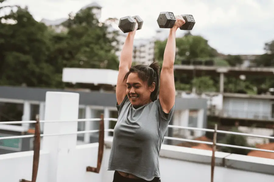 Image of a woman lifting dumbbells overhead. 