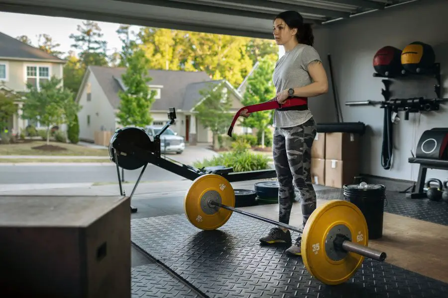 Image of a woman deadlifting in an open garage gym with rubber flooring.