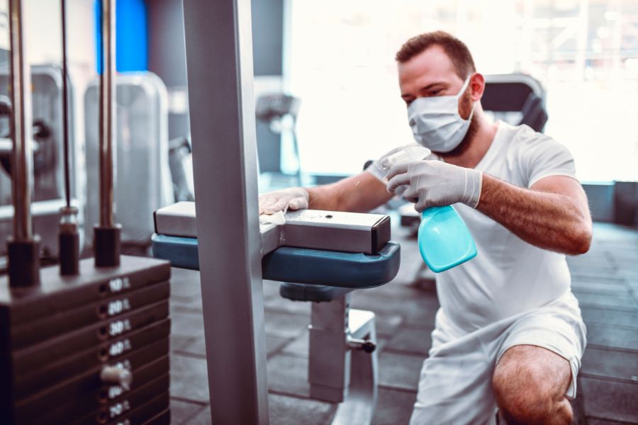 Image of a man wiping down gym equipment