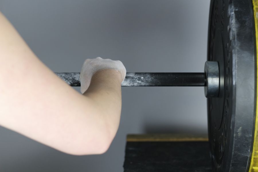 Image of a person holding a barbell with chalky hands.
