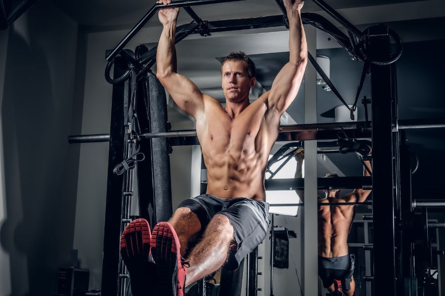 A man doing hanging leg raises on a functional trainer. 